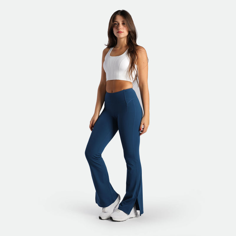 a fit woman wearing crop top  white with flared legging Poseidon blue ,plus the shoes white 