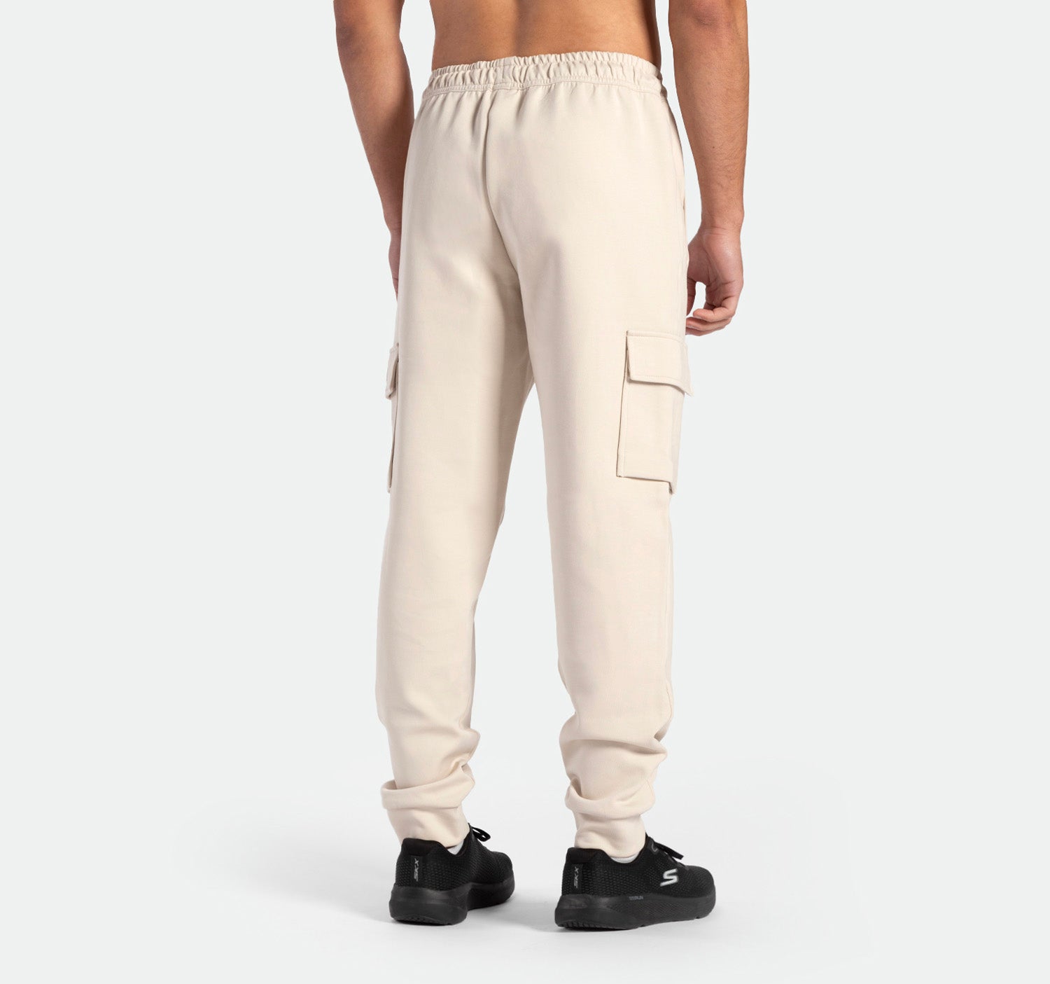 a back view for fit man wearing  jogger pants light  beige with shoes 
black 