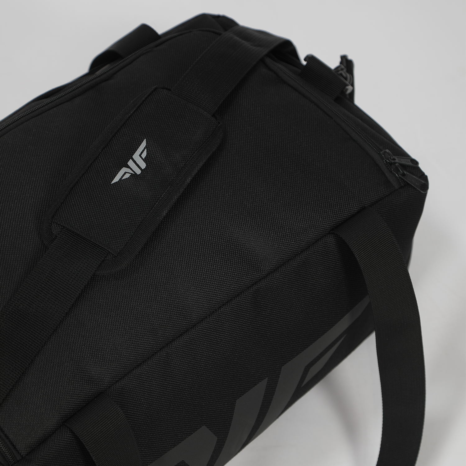 A sleek black duffel bag with two sturdy handles and a subtle embossed logo. Set against a light background, the bag exudes a modern, minimalist vibe.