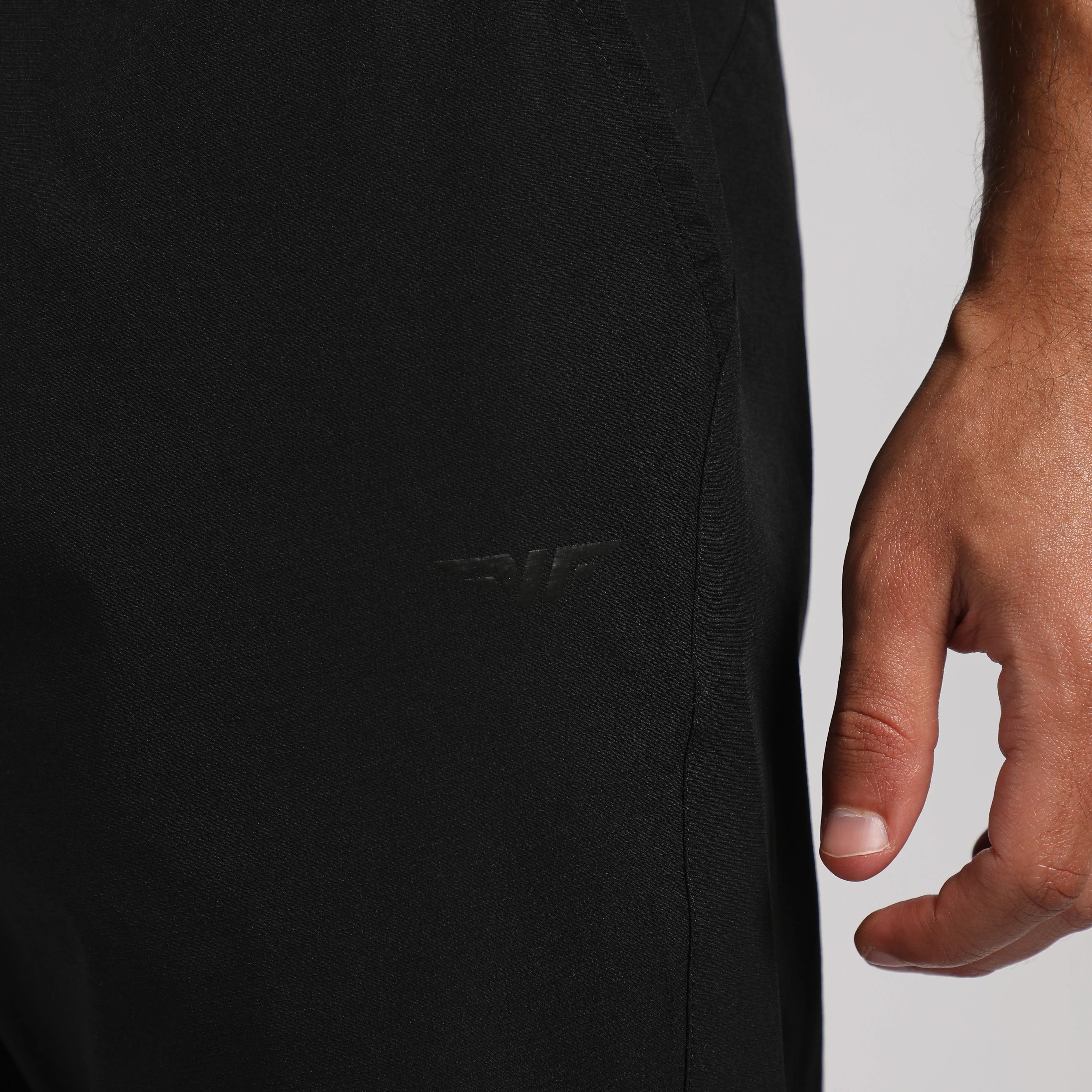 Close-up of a black jacket with a brand logo and a hand touching the fabric.