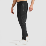 a fit man stand at right and wearing pants black ,plus the shoes white 