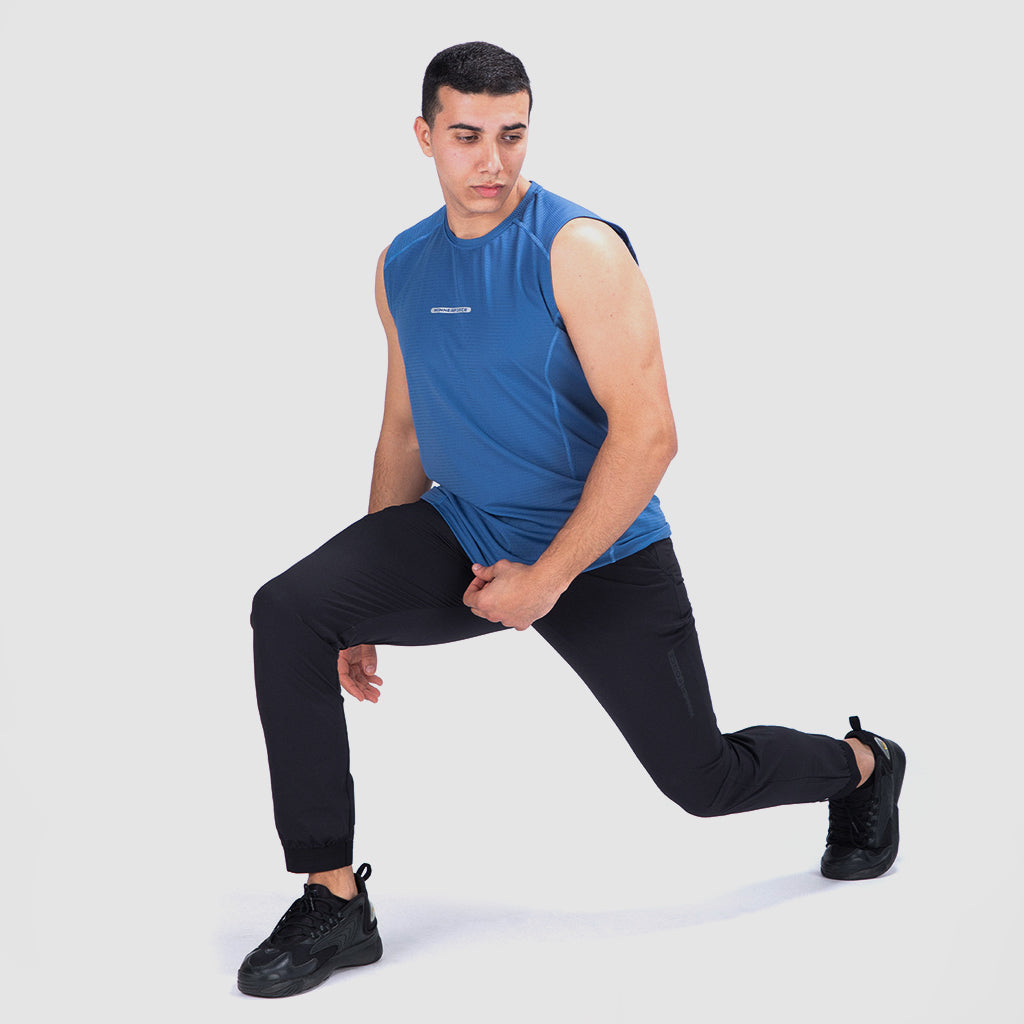 a fit man stand at right and wearing t-shirt blue with pants black ,plus shoes black 
