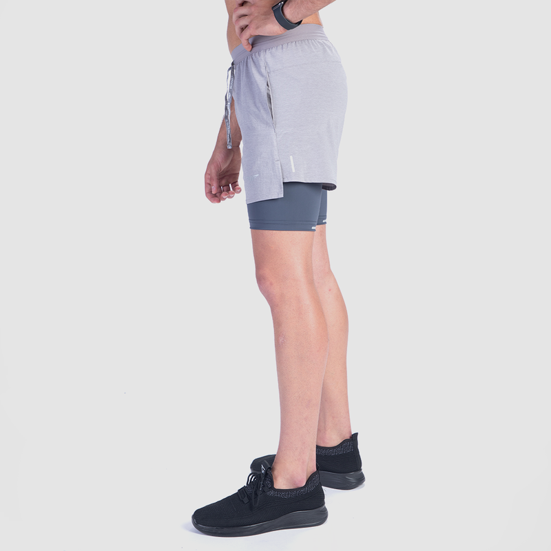 a fit man stand at right and wearing short grey 2 in 1 with shoes black 