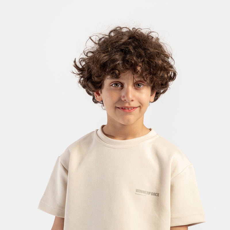 close up view for boy  smile and look at the camera ,he wearing t-shirt light beige with logo 