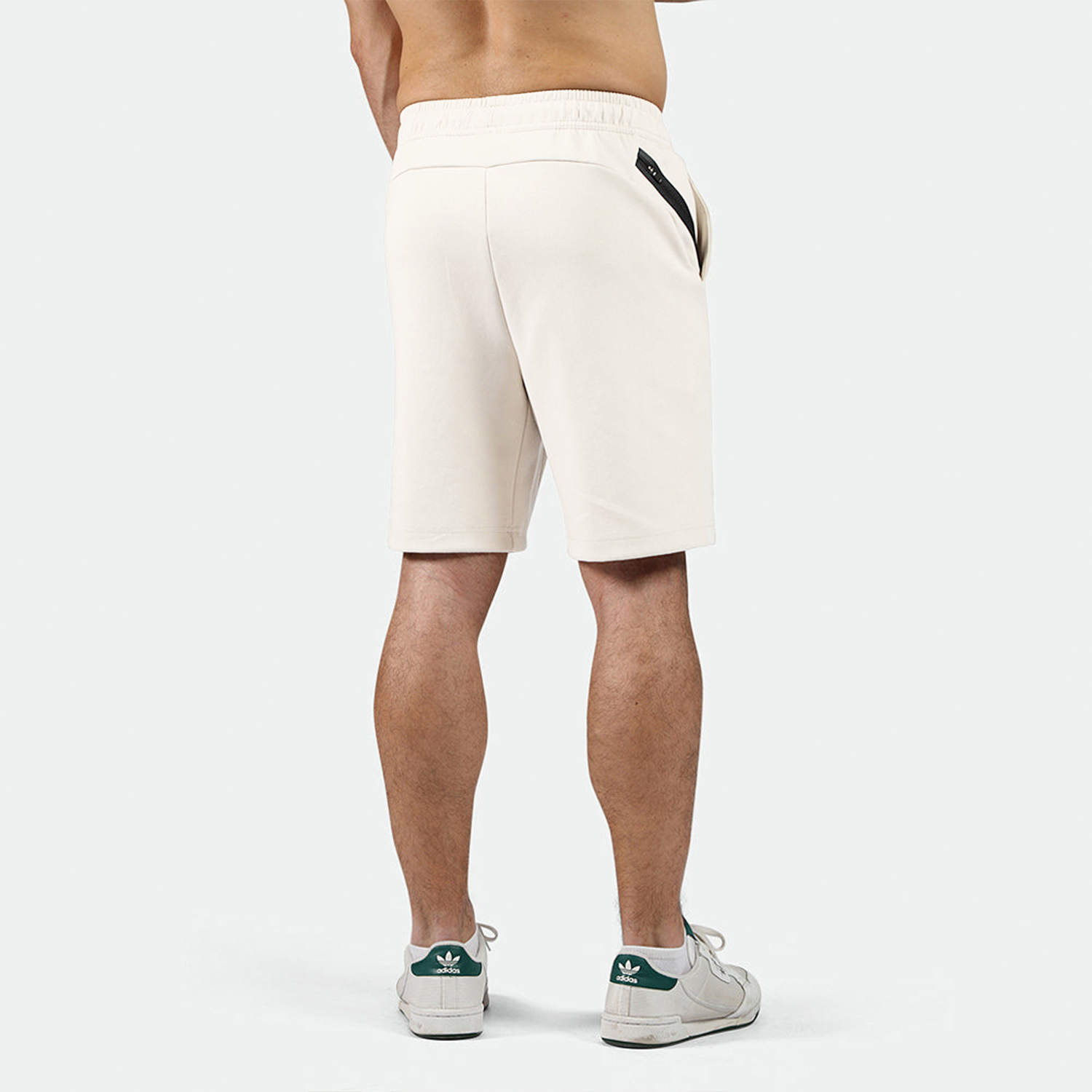 a back view for fit man wearing short beige ,plus the shoes 