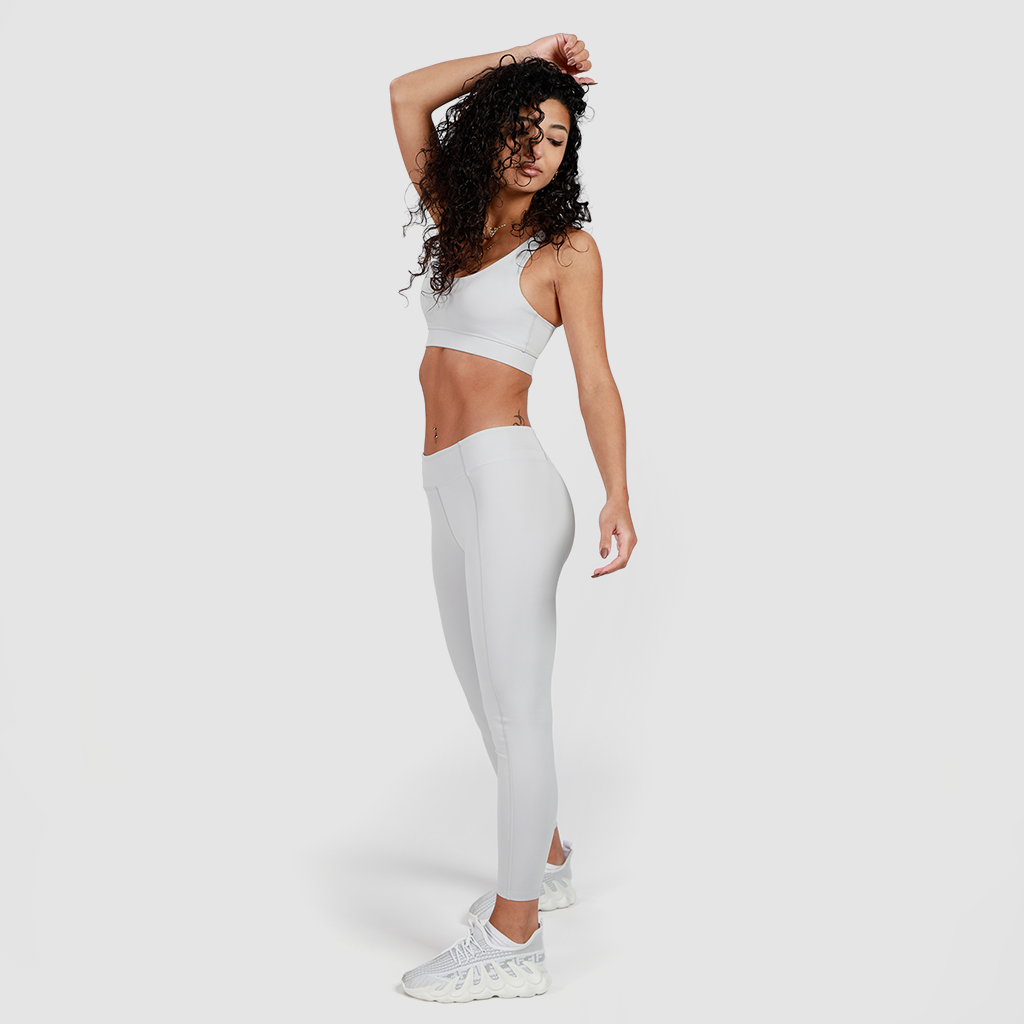 a fit woman wearing  matching bra and legging grey with shoes white, plus the background is light grey 