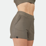 close up view for fit woman wearing short olive grey ,plus the background is light grey 