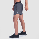 a fit man stand at right and wearing short grey with shoes black 