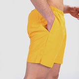 a fit man stand at right and wearing short canary yellow 