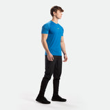 a fit man stand at right and wearing t-shirt azure  blue  with pants black and shoes black 