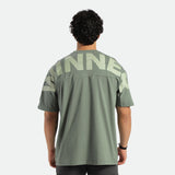 a back view for fit man wearing t-shirt agave green  with pants black 