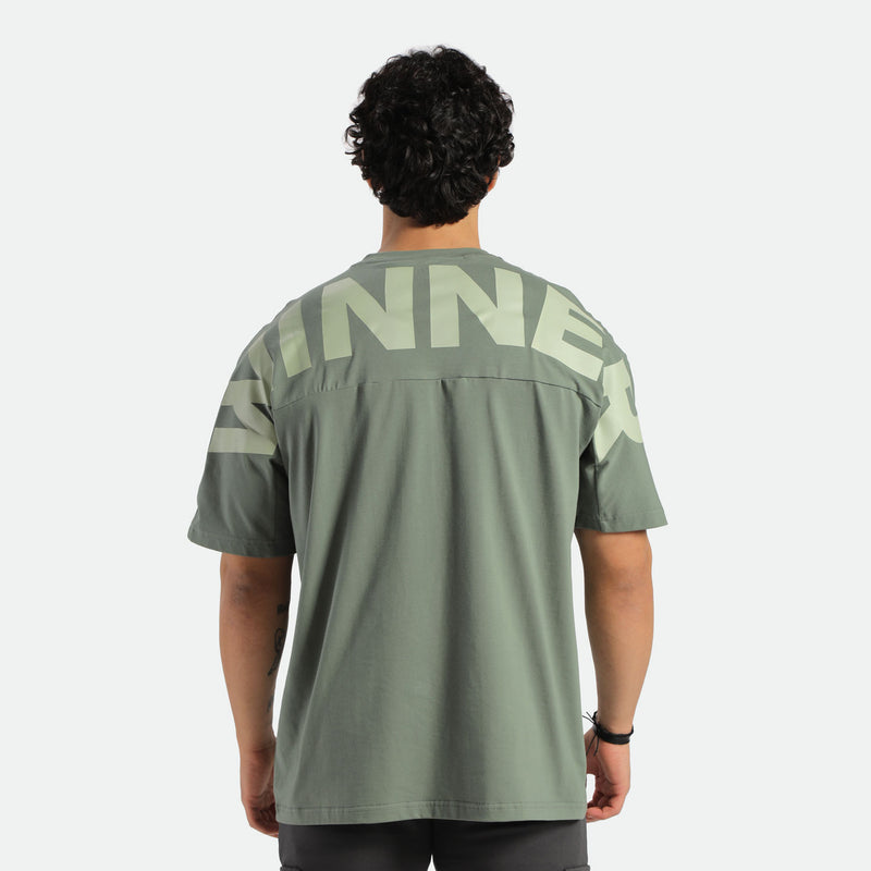 a back view for fit man wearing t-shirt agave green  with pants black 