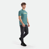 a fit man stand at right and wearing camo t-shirt dark cyan with pants and shoes black 