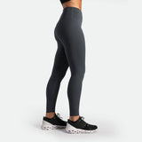 a fit woman stand at right and wearing legging grey ,plus the shoes black 