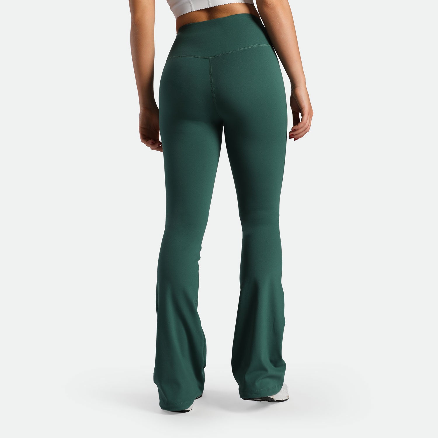 a back view for fit woman wearing flared legging posy green with shoes white 