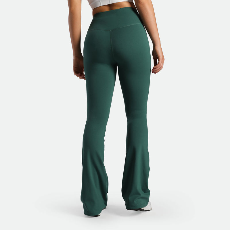 a back view for fit woman wearing flared legging posy green with shoes white 