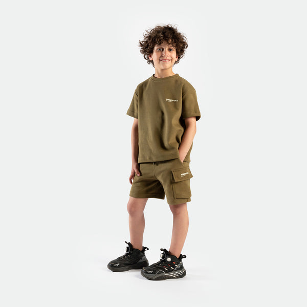 a fit boy look at the camera and wearing  matching set olive drape ,t-shirt and short ,plus the shoes 