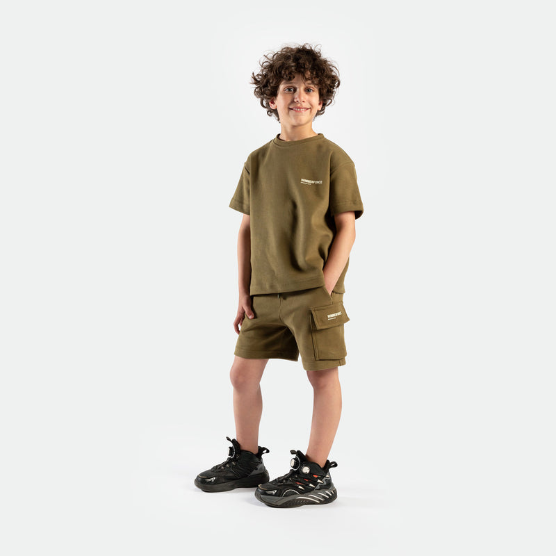 a fit boy look at the camera and wearing  matching set olive drape ,t-shirt and short ,plus the shoes 