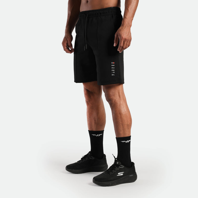 a fit man stand at right and wearing  short black with logo and lace ,plus the socks and shoes black