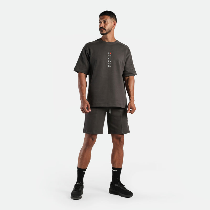 a fit man wearing matching set iron dark grey , t-shirt with logo and short ,plus the socks and shoes black 