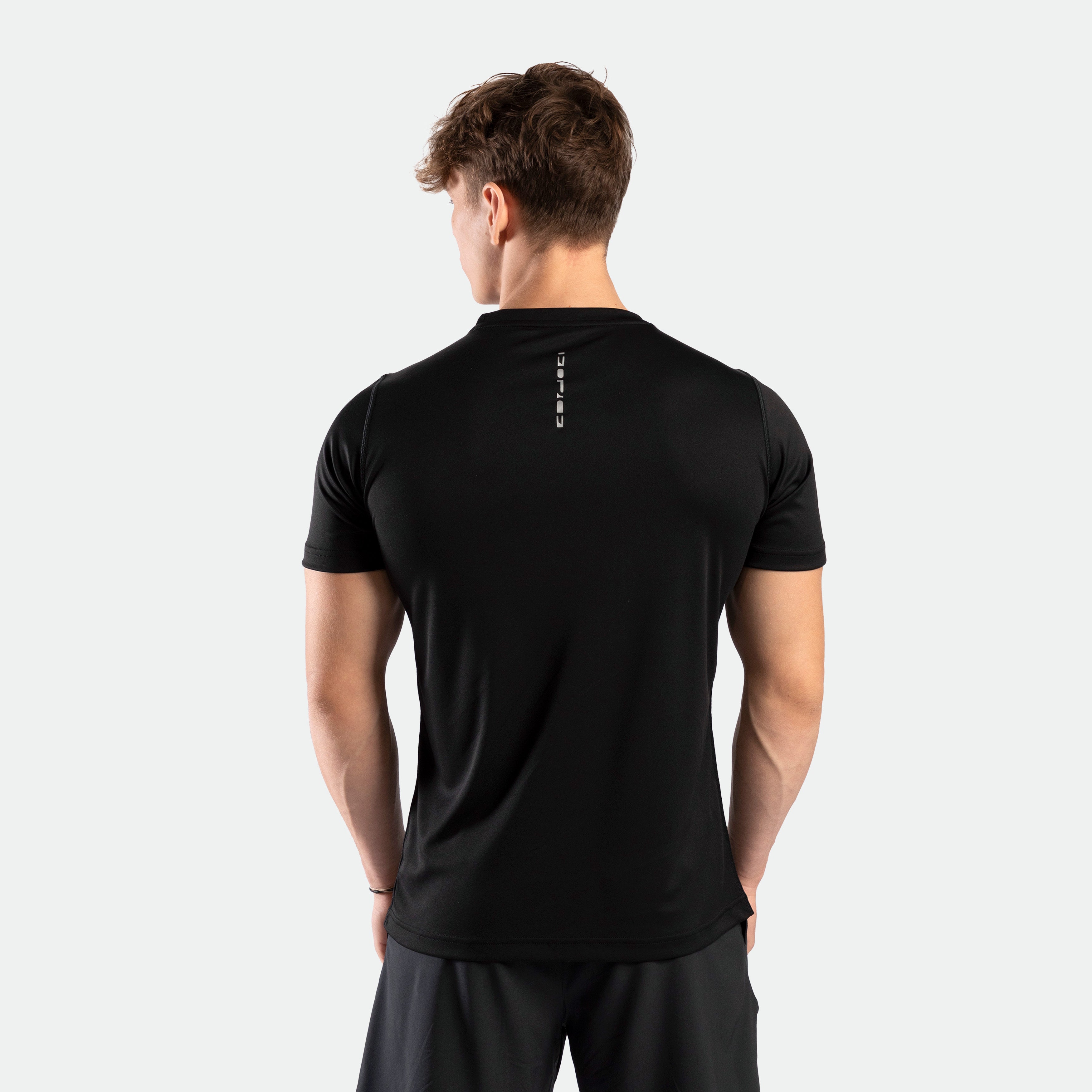 Back view close-up of a man wearing a performance fit t-shirt in the color black. He is also wearing the tri short.