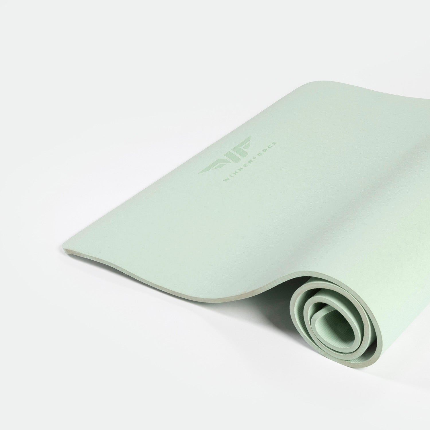 A light green yoga mat, partially rolled, lies on a white background. The mat features a minimalist logo, conveying a calm and serene vibe.