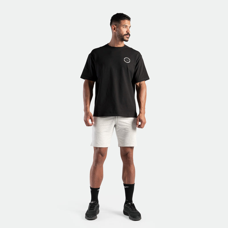 a fit man wearing t-shirt black with logo and short marl light grey , plus the socks black with shoes 