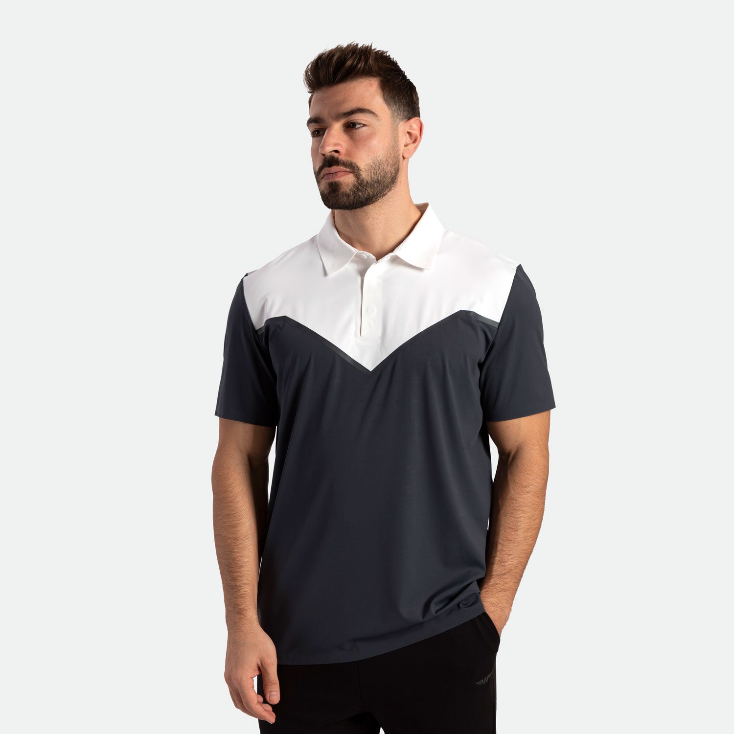 Man wearing a navy and white polo shirt with a chevron design, looking off to the side. The background is plain white, and he appears relaxed.