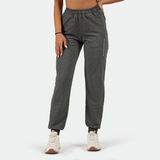 a fit woman wearing  grey jogger pants with shoes black ,plus the background is light grey 