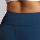 Close-up of a person wearing a navy blue athletic skirt with "WINNERFORCE" embossed on the waistband. They have a white scalloped sports top.
