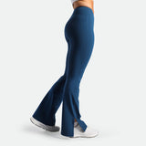 a fit woman stand at right and wearing flared legging Poseidon blue with shoes white 