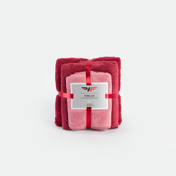 A neatly folded towel set includes burgundy and pink towels, tied with a red ribbon. The packaging label highlights "Towel Set" and gives a sense of luxury.