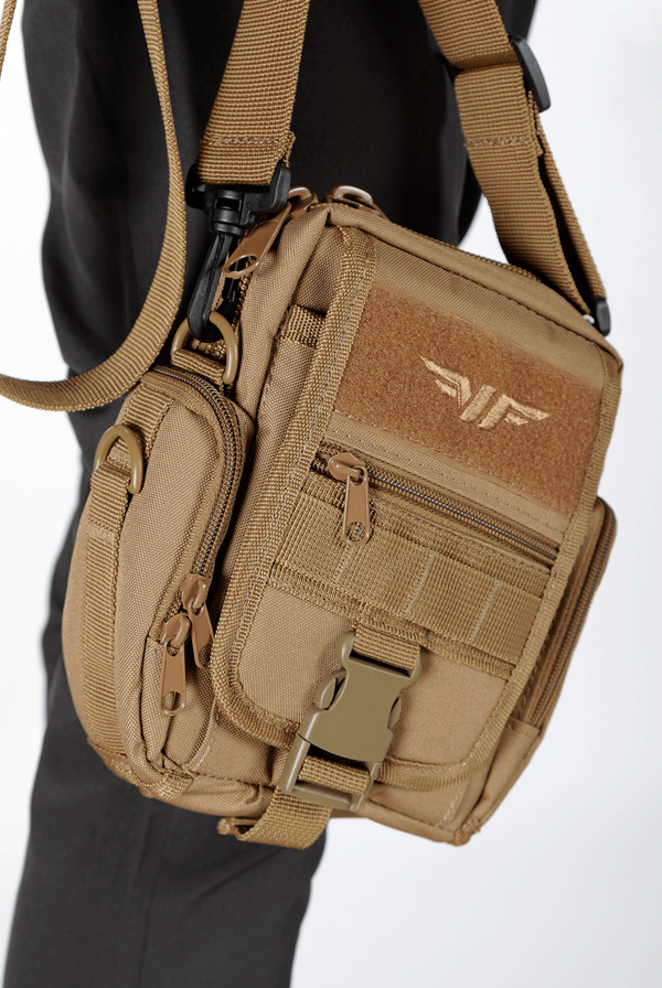 close up view for A small, tan tactical pouch with multiple zippered compartments, side pockets, a front buckle, and a winged logo on the upper front. The pouch is displayed upright against a plain white background.