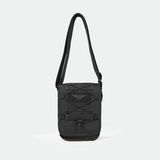 A small, black crossbody shoulder bag with an adjustable strap, front elastic cord, and a subtle logo on the front, displayed against a plain light gray background.