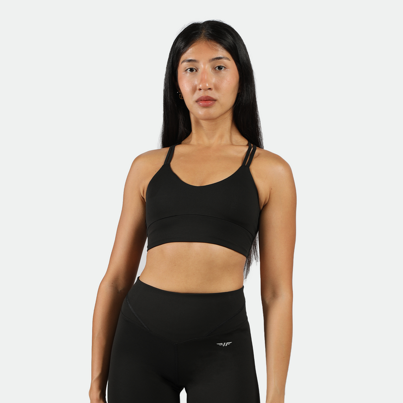 A fit young woman with dark hair in a   black sports bra and matching leggings ,its is have  logo