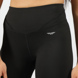 a fit woman wearing legging black with logo white , plus background light grey 