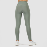 a back view for woman wearing legging green with shoes white, plus the background is light grey 