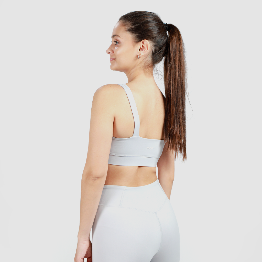a back view  for woman wearing matching grey bra and legging ,with background light grey  