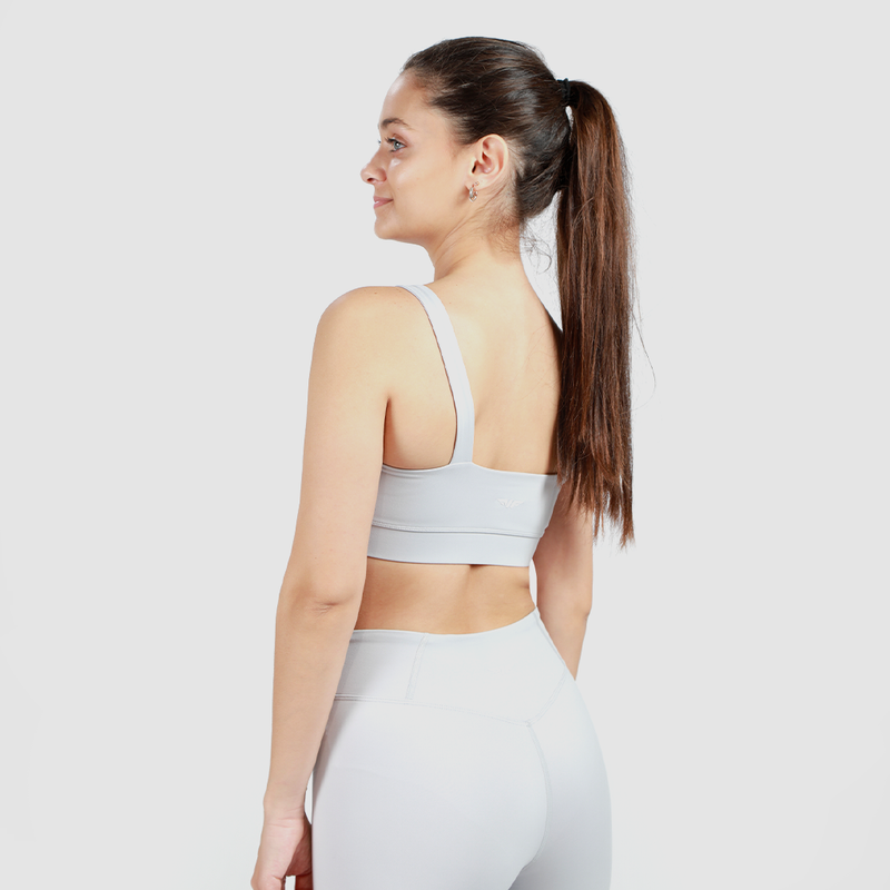 a back view  for woman wearing matching grey bra and legging ,with background light grey  