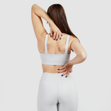 a back view for woman wearing matching grey bra and legging ,plus logo and background light grey