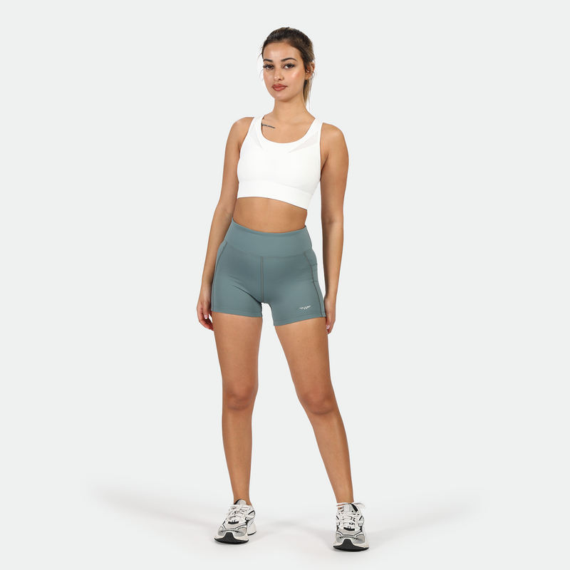 a fit woman look at the camera ,she wearing  bra white with short green ,plus shoes 