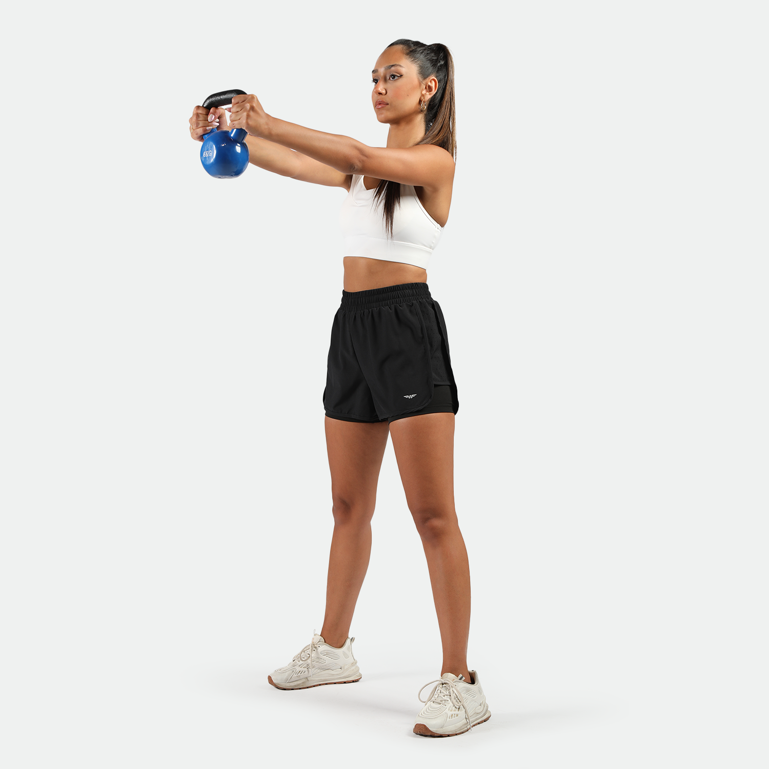 a fit woman wearing sports bra white and black short 2 in 1 with shoes white ,plus the background is light grey 