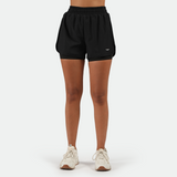 a fit woman wearing black short 2 in 1 with shoes white ,plus the background is light grey 