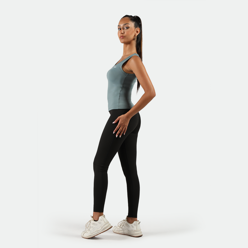 a fit woman stand at right and wearing tank green with legging black 