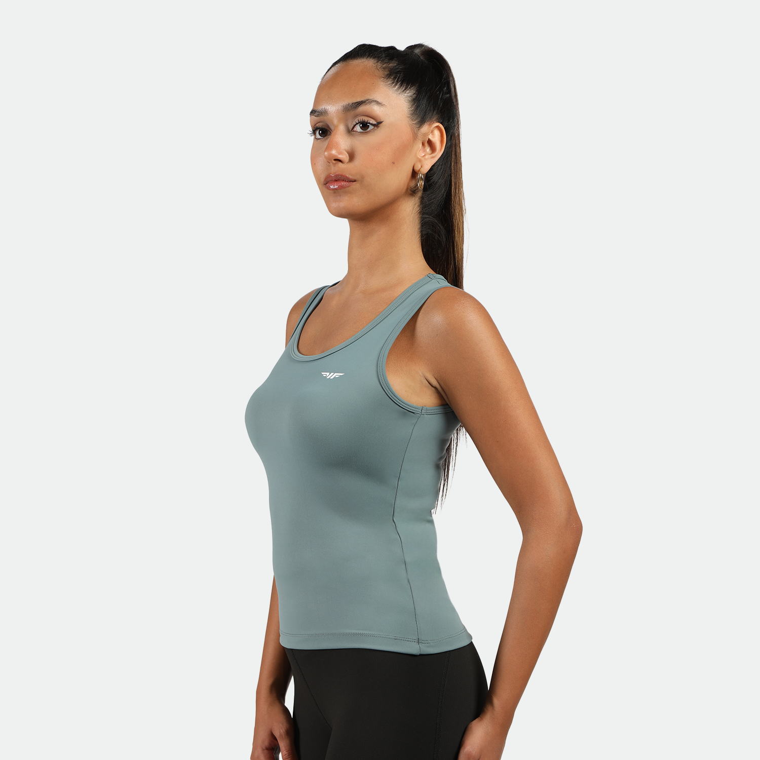 a fit woman stand at right and  wearing tank green with legging black 