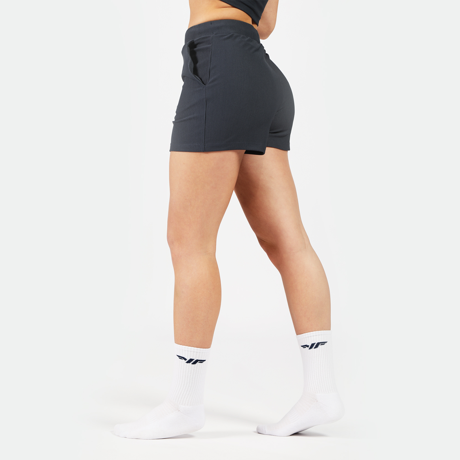 a fit woman stand at right and wearing short grey with socks white 