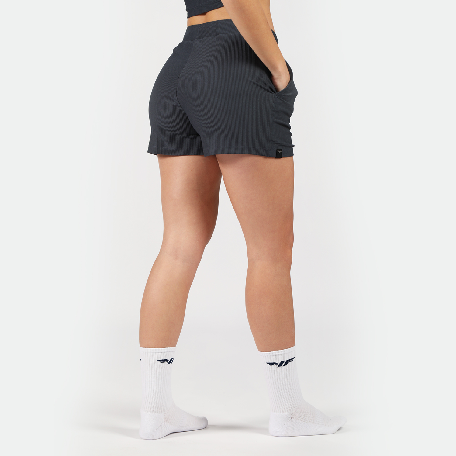 a back view for fit woman wearing short grey with socks white ,plus the background is light grey 