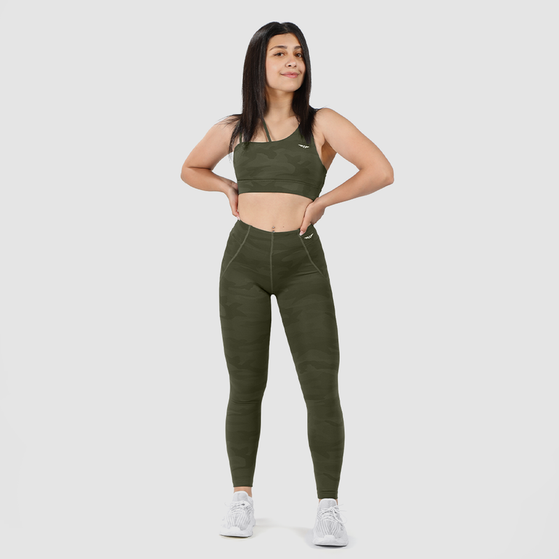 a fit woman wearing matching  olive camouflage bra and legging with logo ,she wearing shoes white ,the background is light grey 