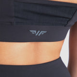 Close-up of woman's back wearing a black sports bra, featuring a subtle logo on the back, white logo (winnerforce)