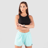 a fit woman stand with pose and look at  right ,she wearing  sport bra black and short sky blue ,plus he background is light grey 